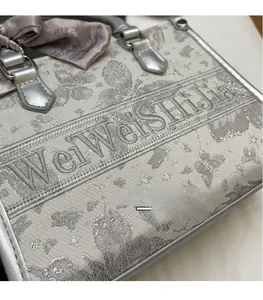 Detailansicht der Schmetterlingsstickerei und Seidenschal am grauen Luxus-Shopper