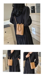Détail du mini sac seau en cuir grainé marron montrant les poignées et le profil latéral