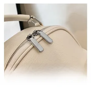 Close-up of premium silver zipper and soft leather texture on beige casual backpack