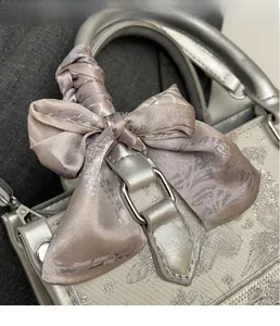 Nahaufnahme eines Seidenschals mit Vintage-Blumenmuster an einer silbernen Glitzertasche