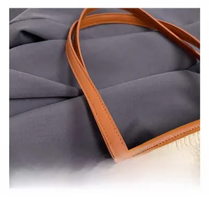 Close-up of woven straw tote bag with brown leather handles and fine stitching details