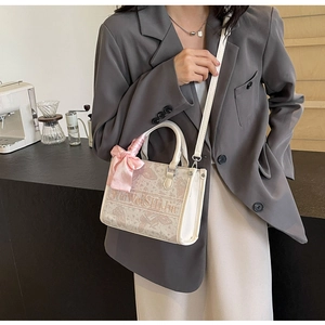 Detail einer schicken cremefarbenen Tasche mit Schmetterlingsdruck und Seidenschal