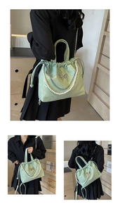 Detalle del bolso verde menta brillante con adorno de mariposa, perlas y cierre de cordón