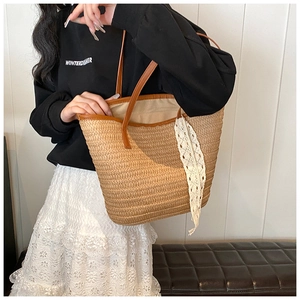 Close-up of woven straw tote bag featuring brown leather trim and delicate white lace detail