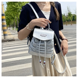 Detail view of silver pleated backpack with metallic finish and pearl drawstring accents