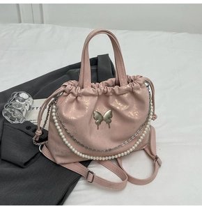 Detalle del bolso rosa metalizado con broche de mariposa y cadena de perlas