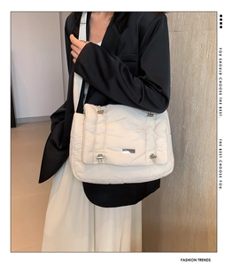Detail van witte gewatteerde crossbodytas met zilveren sluiting gedragen door een model
