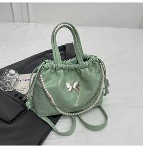 Bolso de cuero verde menta con emblema de mariposa plateada y cadena de perlas fina