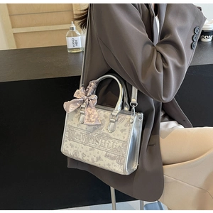 Detail der silbernen Canvas-Handtasche mit Blumendruck und stilvollem lila Seidenschal