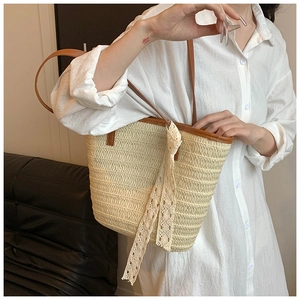 Detail of beige straw tote bag with brown leather straps and white lace ribbon decoration