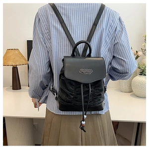 Fashionable black pleated backpack with metal logo and drawstring closure shown on model