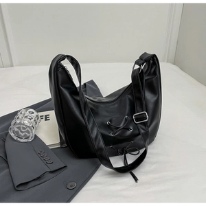 Detail of black crescent tote bag featuring stylish criss-cross lacing and metallic buckle