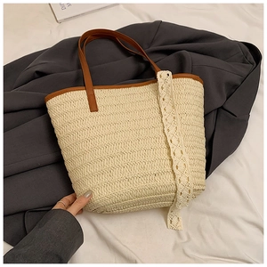 Close-up of woven straw tote bag with delicate white lace trim and brown leather handles
