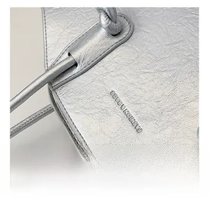Détail du sac argenté métallisé avec texture froissée et lettrage de mode chic