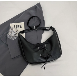 Detail of black leather hobo bag featuring corset-style lace-up design and silver buckle