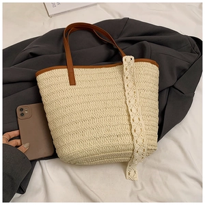 Detail of woven straw tote bag with brown leather handles and delicate white lace trim