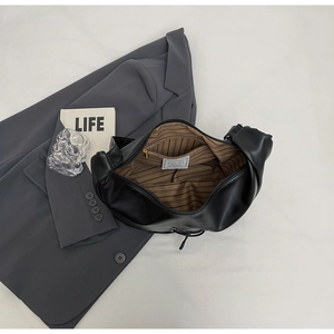 Detail of black tote bag interior showing striped lining and internal zipper pocket