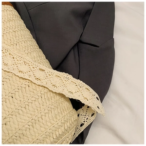 Detailed texture of beige woven straw bag featuring delicate light yellow lace trim accents