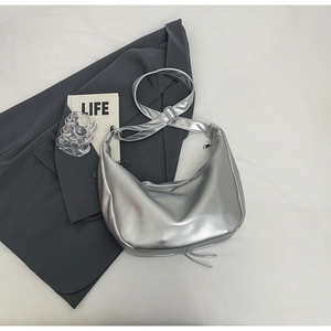 Close-up of metallic silver crescent hobo bag featuring bottom fringe and wide strap
