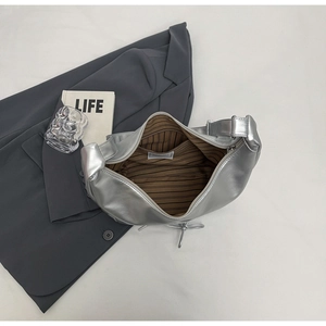 Flat lay of silver metallic crescent bag with brown striped lining and interior zipper pocket