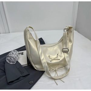 Detail of a creamy white pearl hobo bag with ribbon bows and adjustable strap