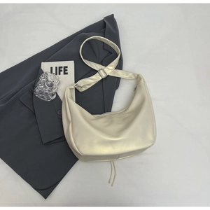 Top view of cream half-moon tote bag with adjustable wide strap on minimalist background