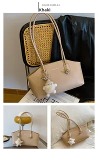 Détail du sac bandoulière kaki avec texture vintage et breloque sur une chaise en rotin