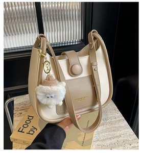 Detail of a beige and brown colorblock bucket bag with a cute plush sheep charm