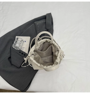 Detalle del interior del bolso bombonera blanco con cordón, asa de perlas y cadena metal