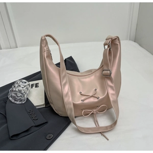 Detail of champagne satin hobo bag with ribbon bow on a grey suit jacket background