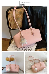 Détail du sac à épaule rose en similicuir avec texte FASHION & BAGS et pendentif