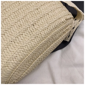 Close-up of woven straw bag showing fine texture and white lace crochet shoulder strap