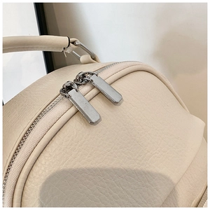 Detail of cream leather backpack featuring silver zippers and neat stitching work