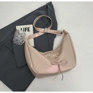 Detail of beige half-moon leather tote bag with ribbon bow and adjustable strap buckle