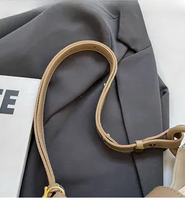Detail of adjustable leather strap with vintage gold buckle on khaki bucket bag
