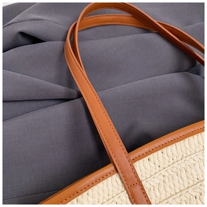 Detail of white woven texture and brown leather strap stitching on summer straw tote bag