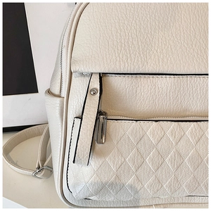 Detail of cream leather backpack featuring litchi texture and quilted zipper pocket