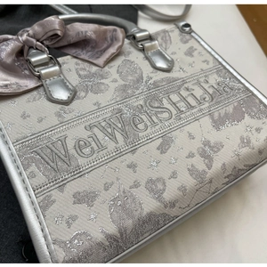 Nahaufnahme der silbernen Sticktasche mit Blumenmuster und rosa Seidenschleife