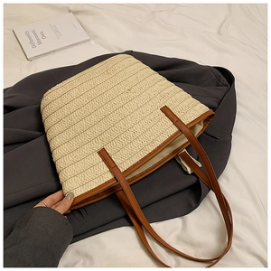 Close-up of woven straw tote bag with brown leather handles and premium fabric lining