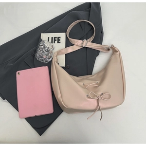 Detail of pink PU leather crescent tote bag with knot bow decoration and long strap