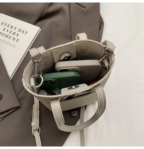 Top-down view of a light grey bucket bag showing spacious interior with two smartphones