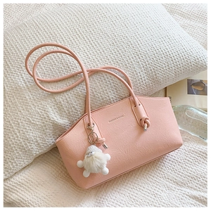 Détail du sac sous le bras en cuir rose doux avec poignée nouée et breloque peluche