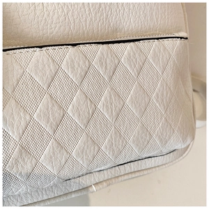 Detail of white quilted faux leather texture and premium stitching on trendy backpack