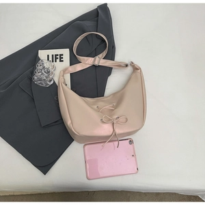 Detail of light pink crescent tote bag with decorative drawstring bow and gray blazer