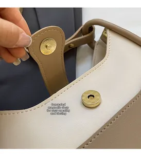 Detail of magnetic snap closure on contrast leather bucket bag with golden hardware