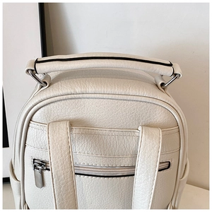 Detail of lychee pattern faux leather backpack showing handle and back zipper pocket
