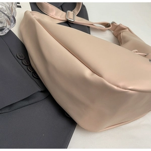Detail view of beige matte leather hobo bag with silver buckle on a grey blazer