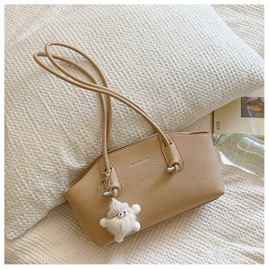 Détail du sac bandoulière beige plissé avec longues anses et pendentif peluche