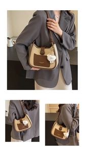 Detail of a beige and brown contrast hobo bag with a cute white plush lamb pendant