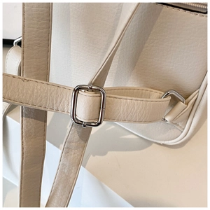 Detail of beige pebble leather shoulder strap with silver metal buckle on a casual backpack